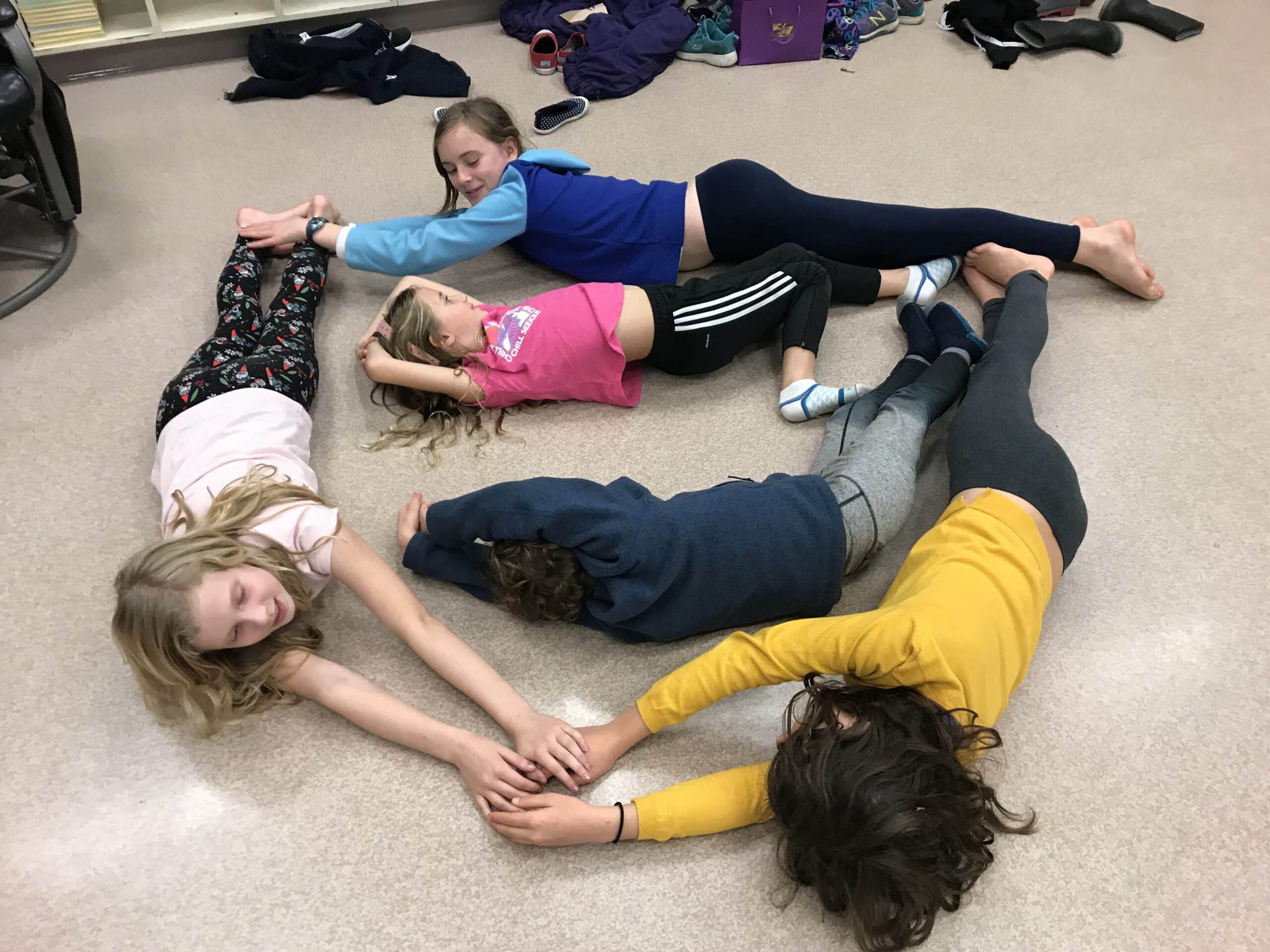Students on floor making a circle in a story from the class.
